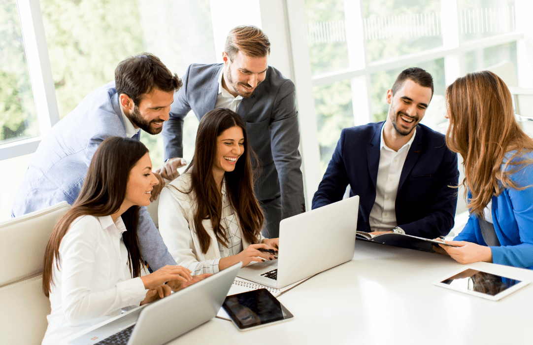 Buiness team looking at laptop and smiling around board table