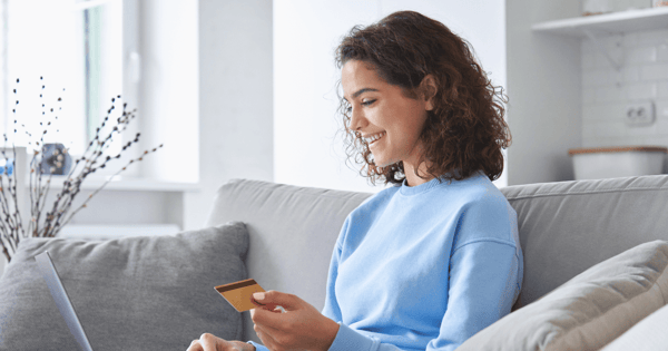 Consumer using her laptop and card and smiling