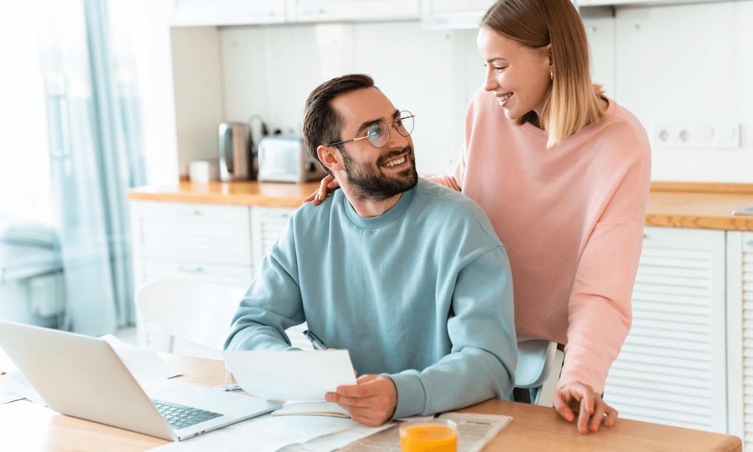 Couple doing their finances in the kitchen at home and smiling