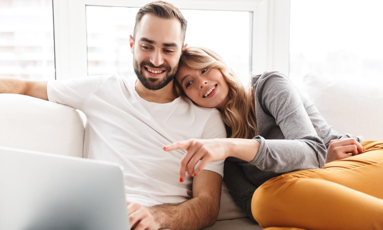 Couple doing their finances on the sofa with laptop at home