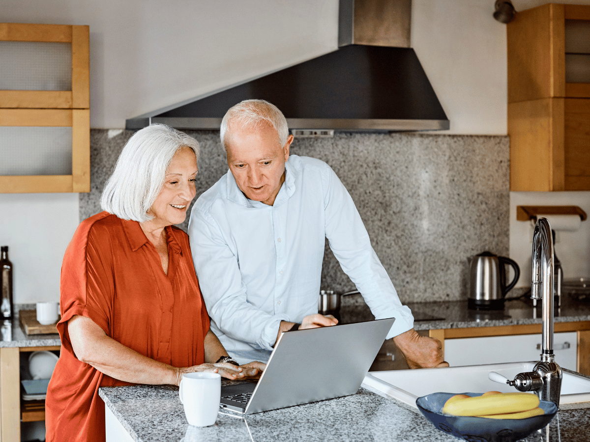 Older couple in kitchen using free secure email on laptop