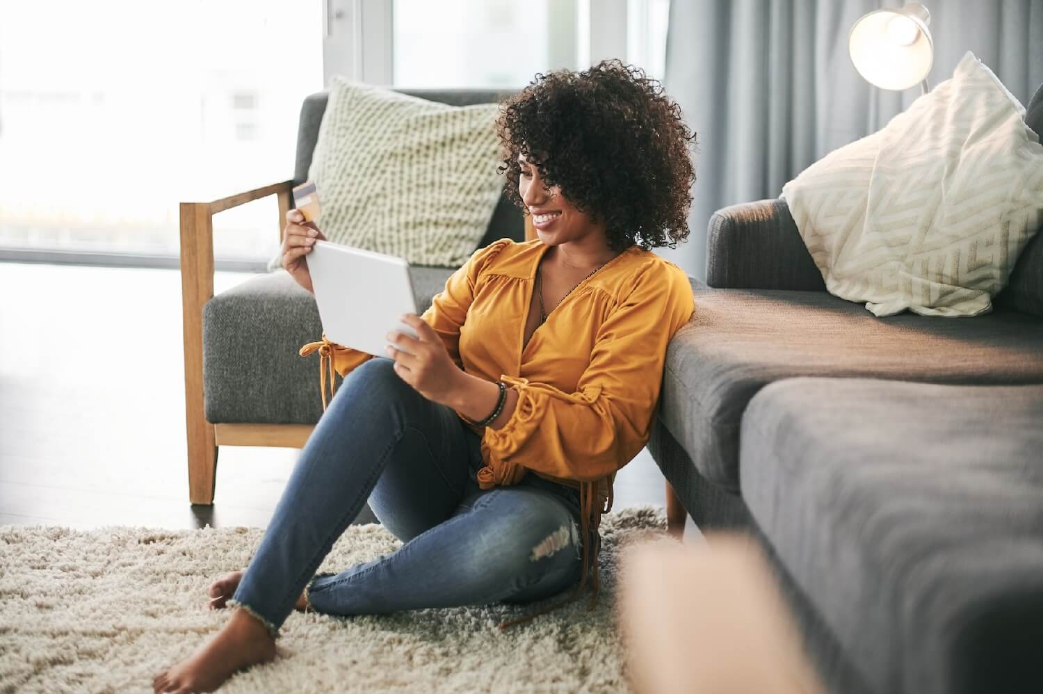 Customer sitting in living room on floor looking at tablet