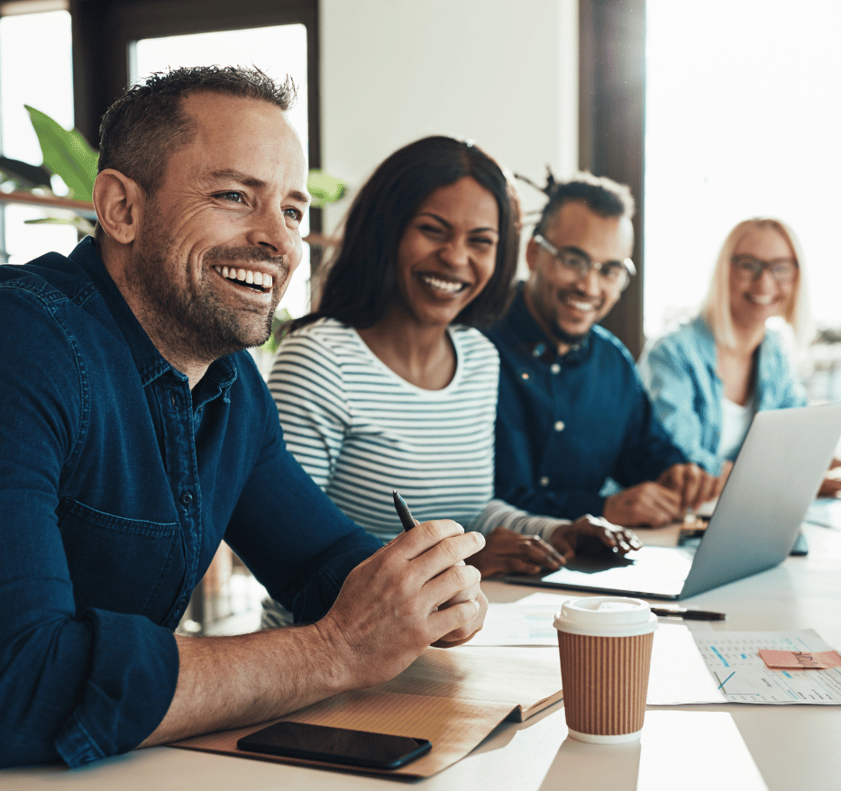 Leaders smiling at board table with laptop