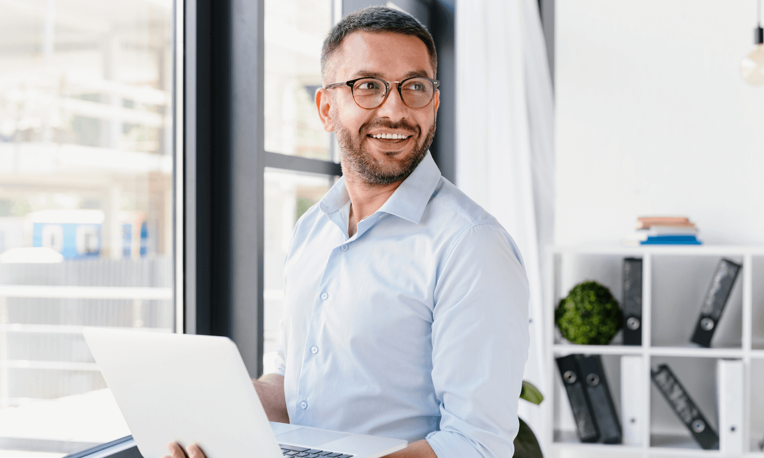 Man looking happily in enterprise office with laptop
