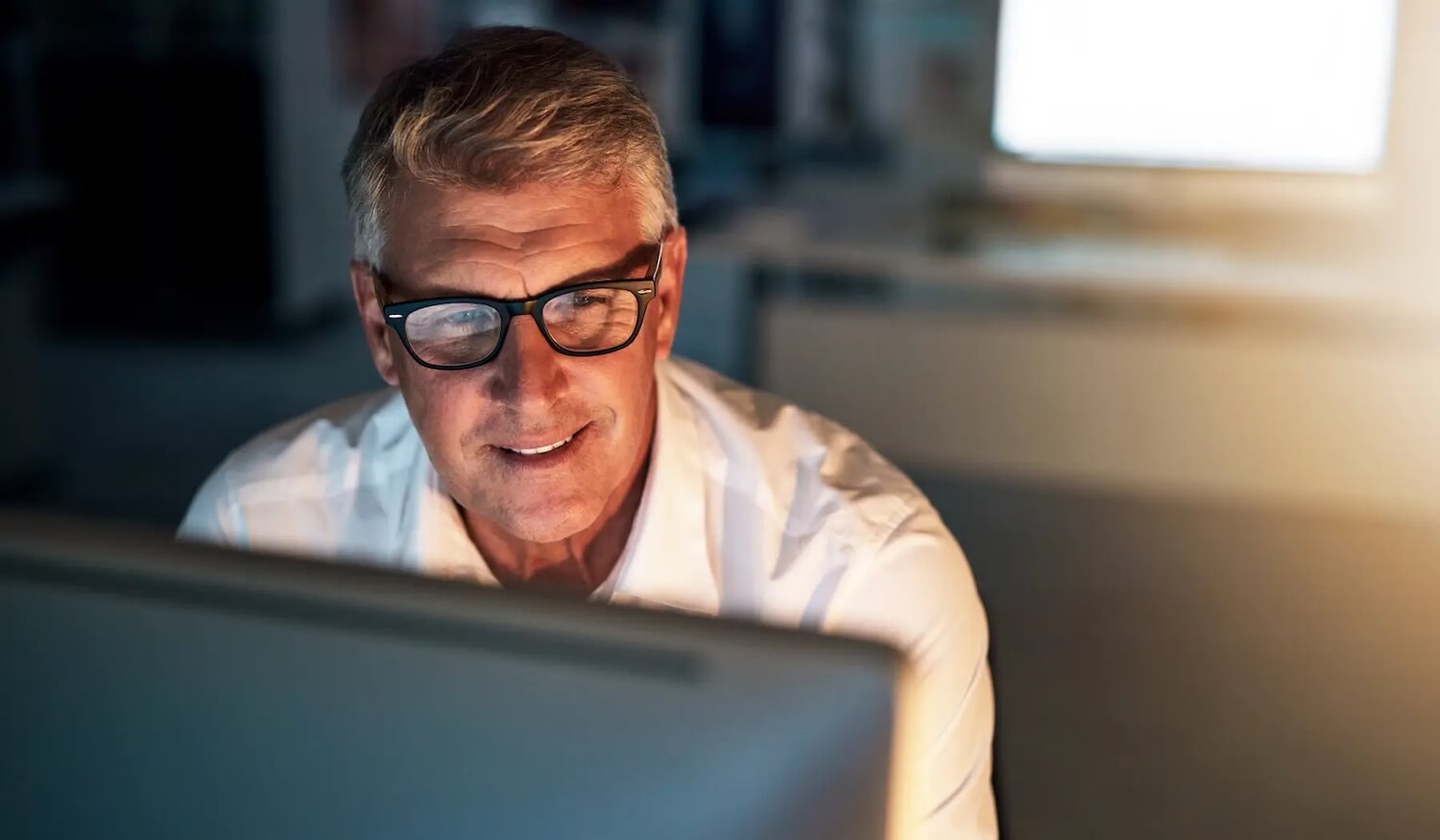 IT professional sitting at computer at night smiling at screen with secure email