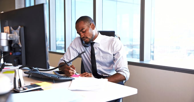 Professional man on phone in office in front of desktop