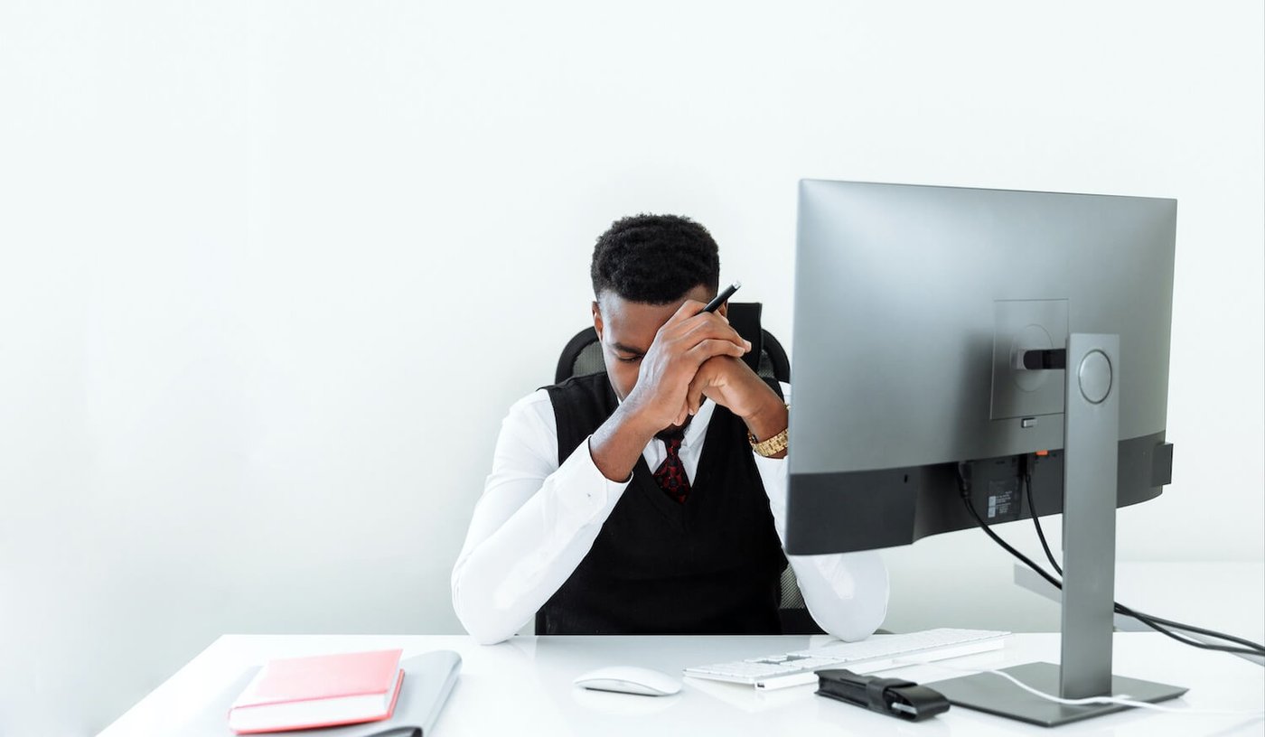 Man stressed at desk with computer in office