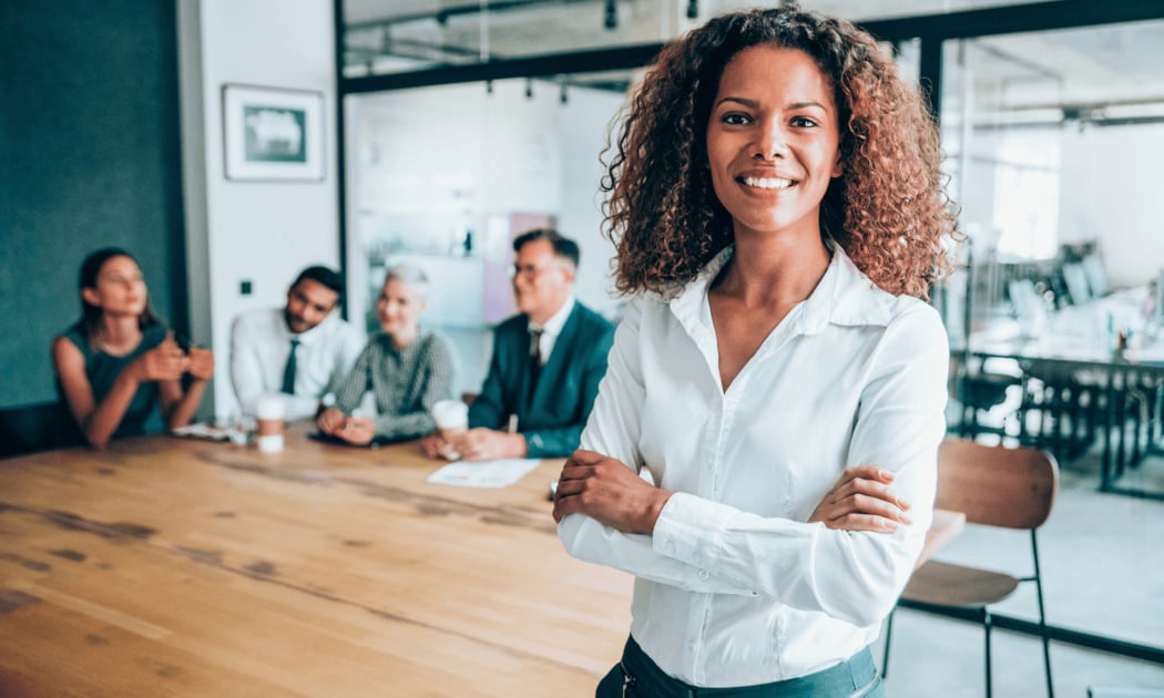 Professional woman standing in office with crossed arms smiling