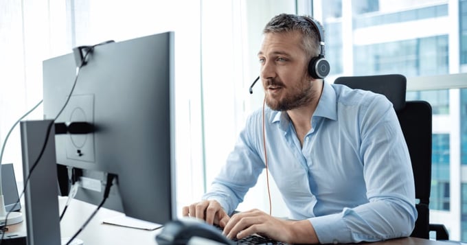 Male professional with headset using desktop computer