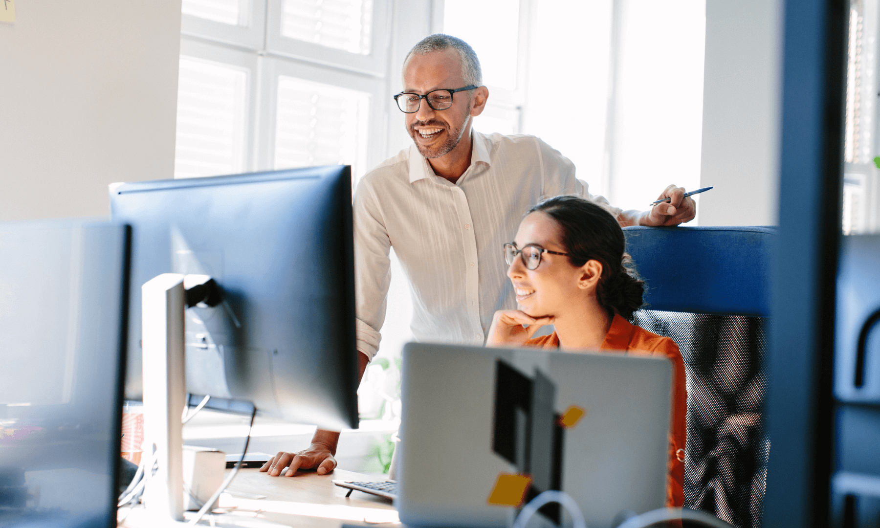 man and woman looking at computer in office