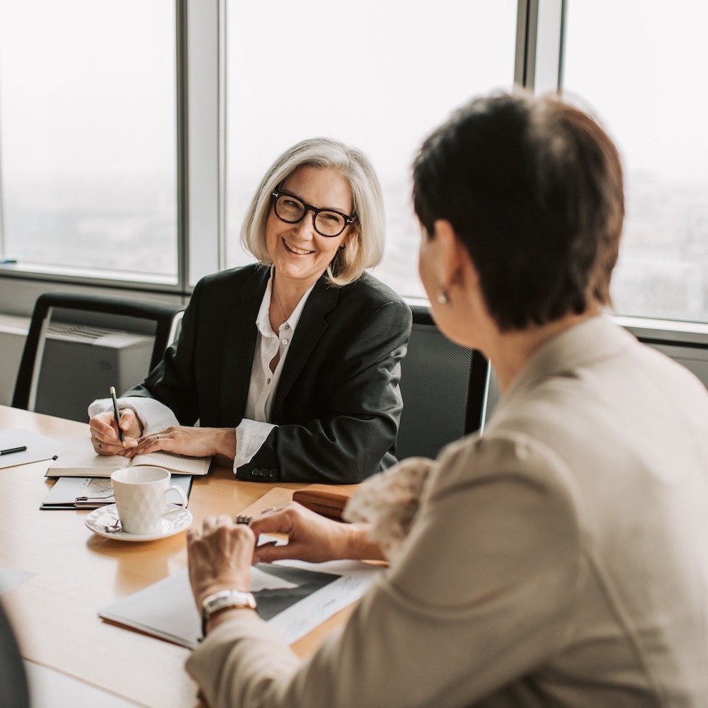 Two female leaders in meeting room discussing secure email automation