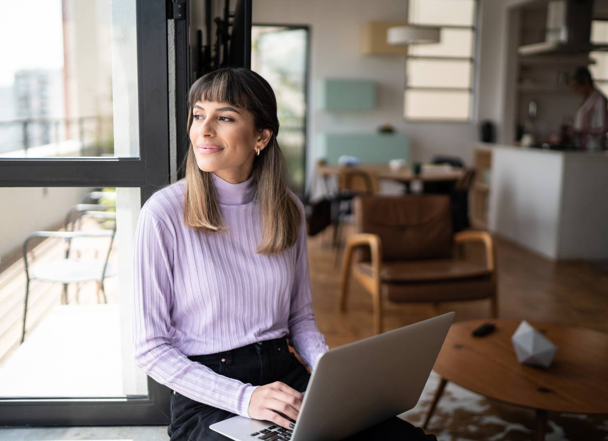 Woman on laptop looking out window