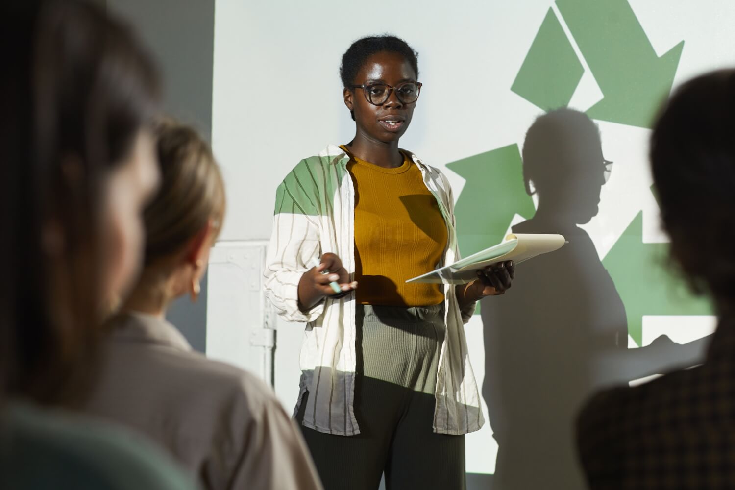 Woman giving talk on sustainability in the office to professionals