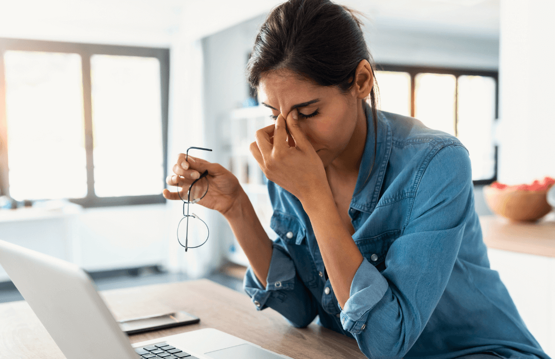 Woman holding head in front of laptop stressed with digital fatigue coloured