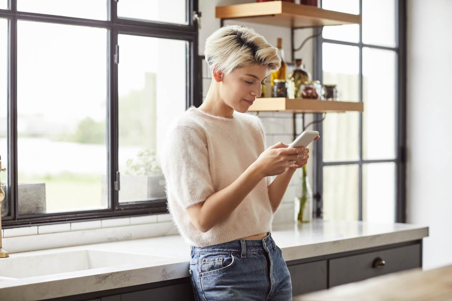 Woman reading secure message on her smart phone in kitchen