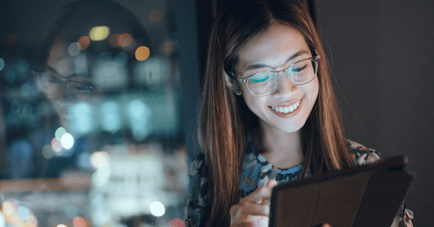 Woman smiling and using tablet at night in office