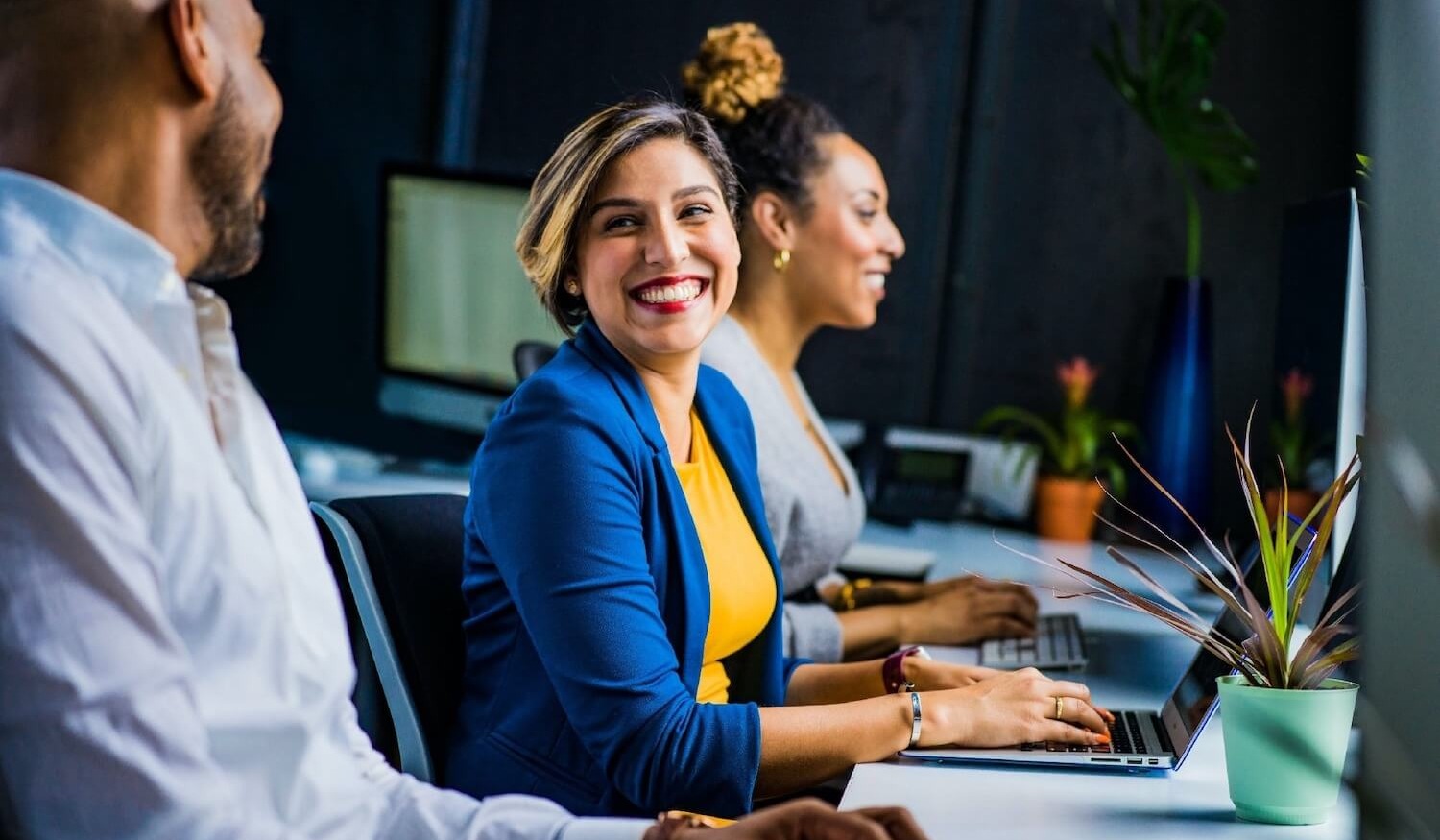 Woman smiling in offer using laptop to secure emails next to colleagues (1)-1
