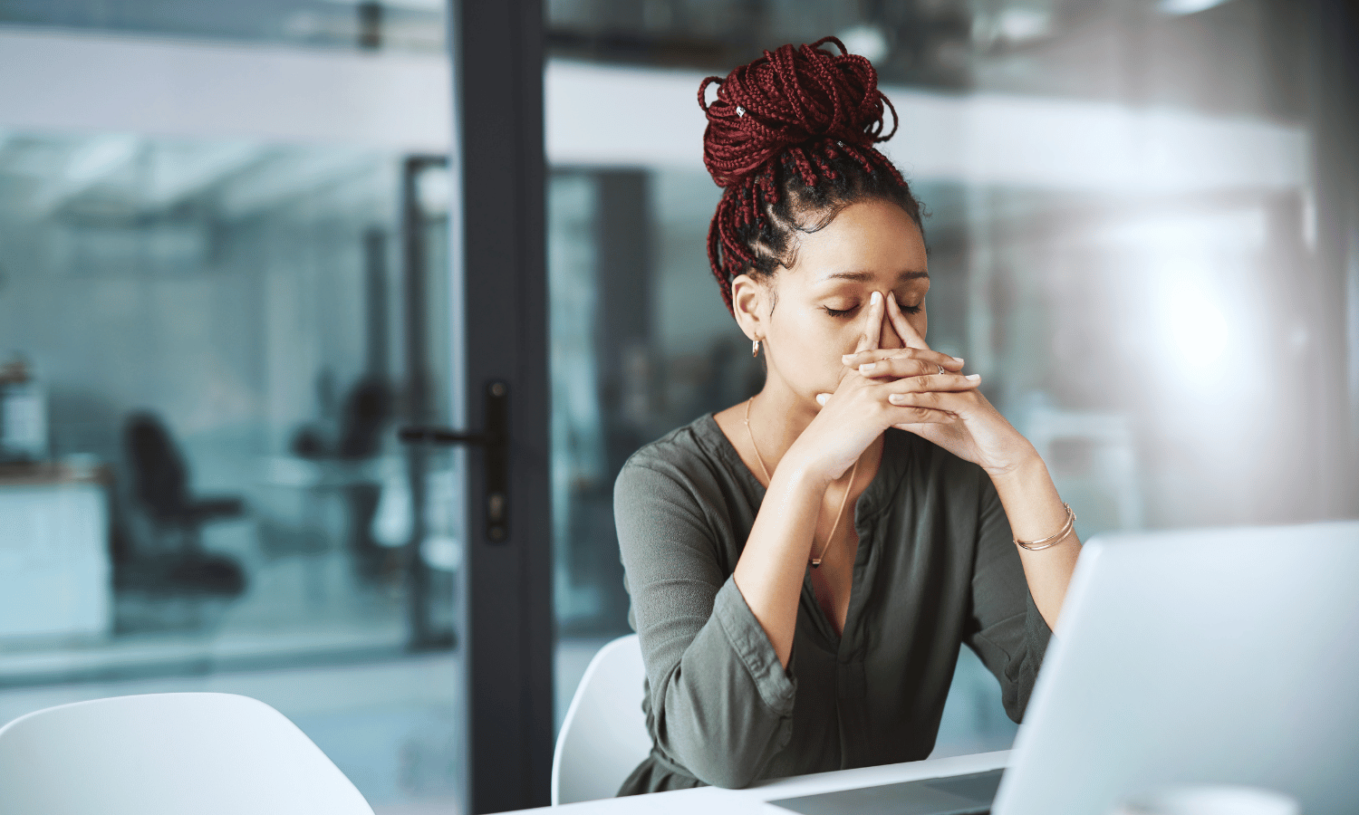 Woman with head in hands at desk with laptop