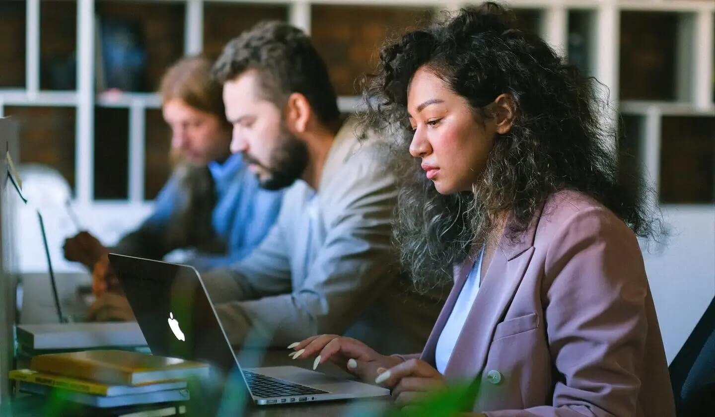 Woman working on laptop next to colleagues looking worried (1)