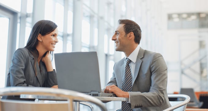 Colleagues talking to each other in office next to laptop