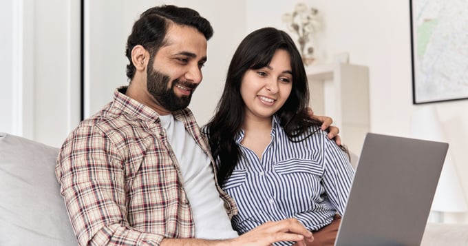 Couple at home using laptop for email on sofa