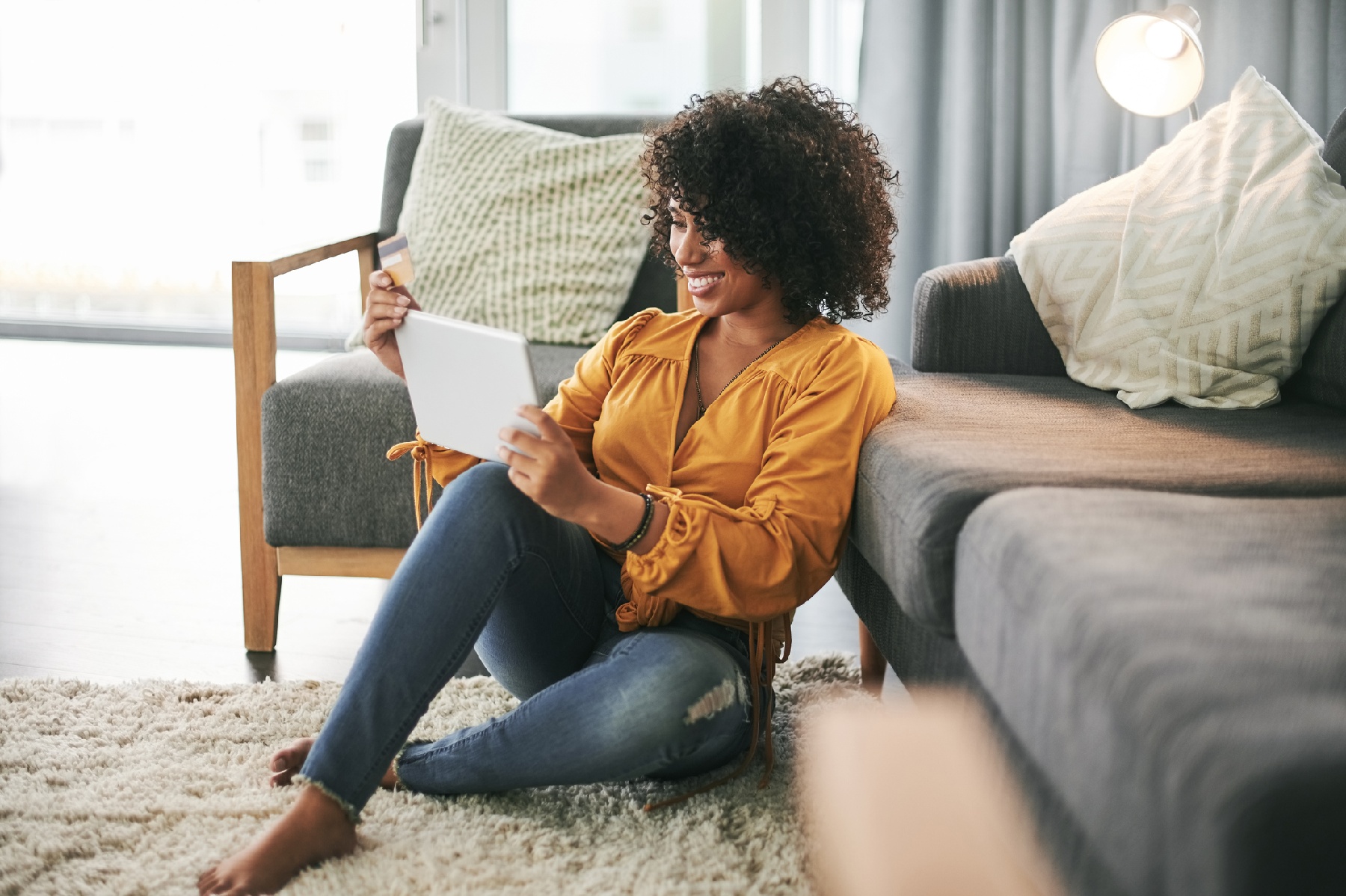 customer sitting in living room on floor looking at tablet