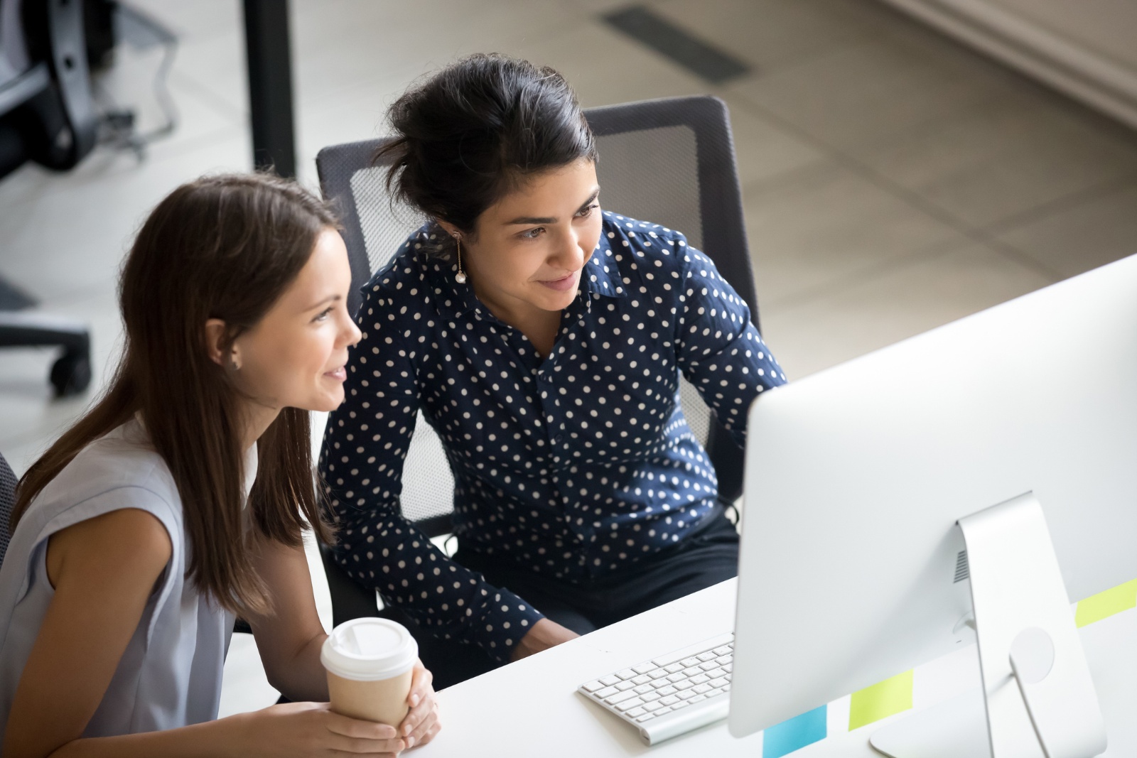 Women looking at screen together in office