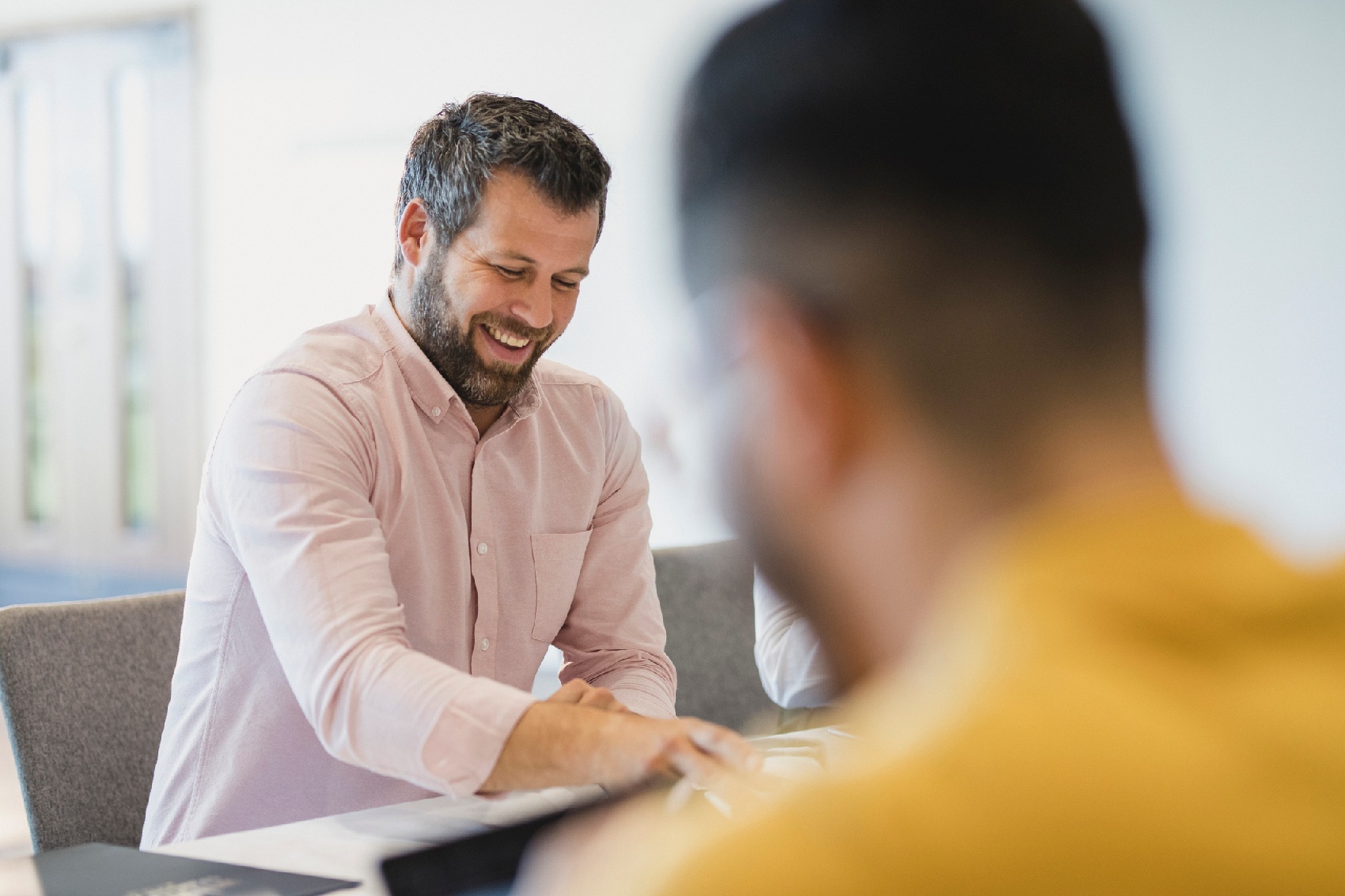 Male professional smiling with colleague in office