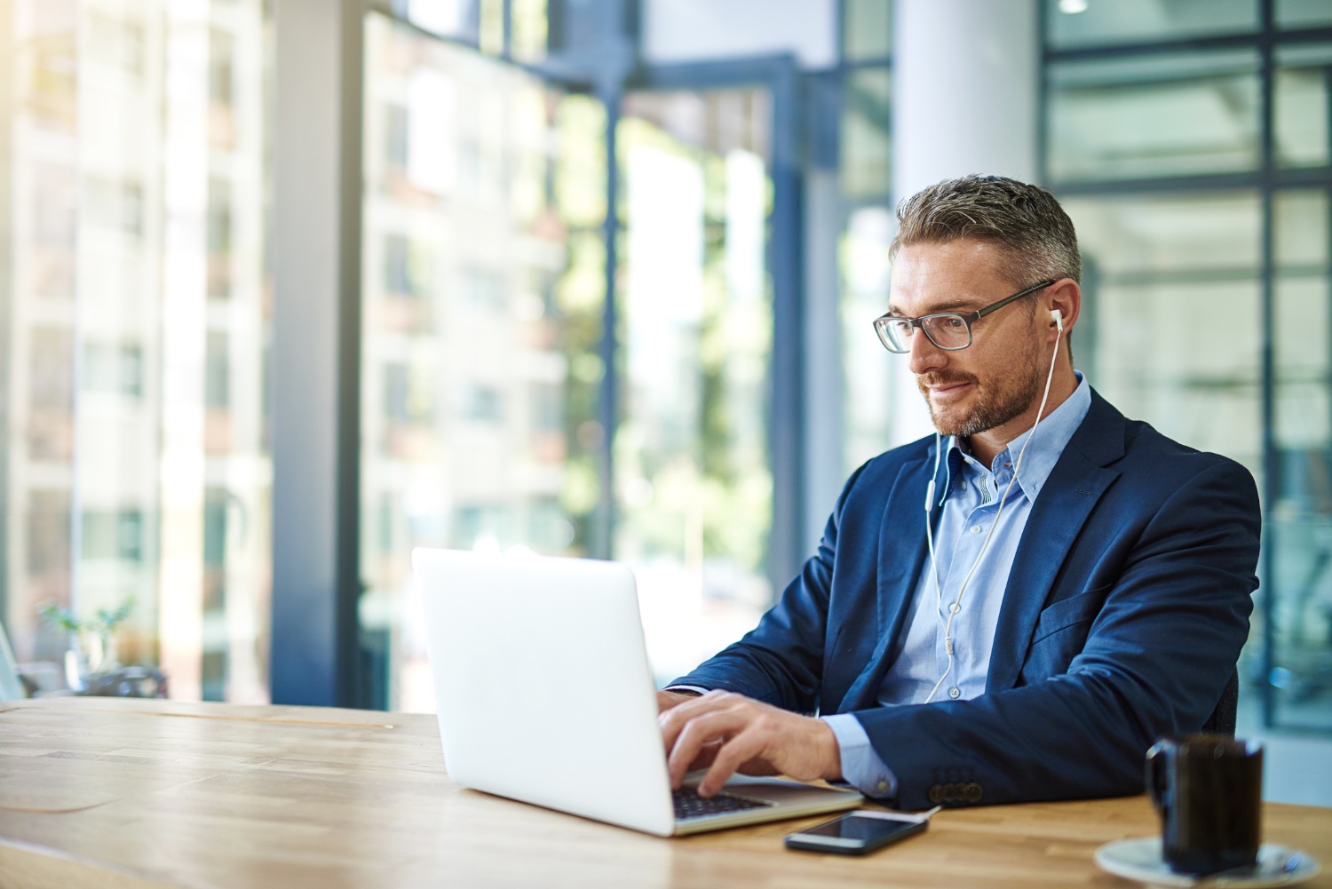 Man encrypting emails in office with earphones in