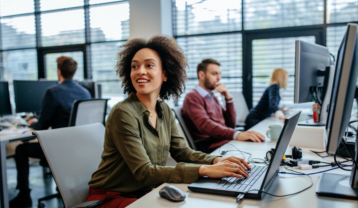 woman in office typing on laptop and smiling