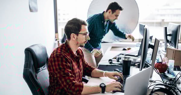 Male IT manager using desktop computer with colleague