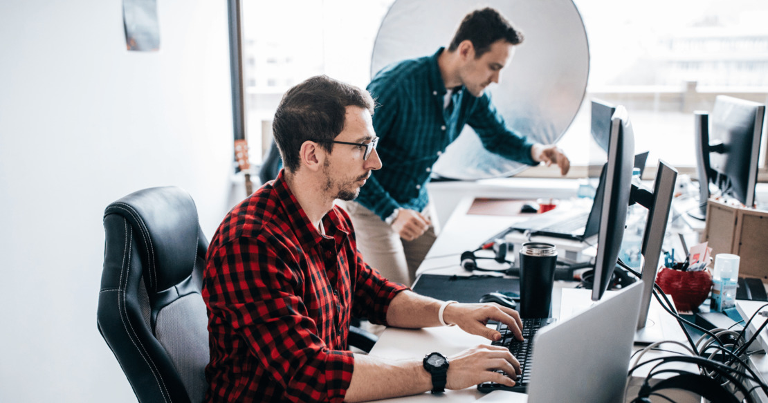 Male IT manager using desktop computer with colleague