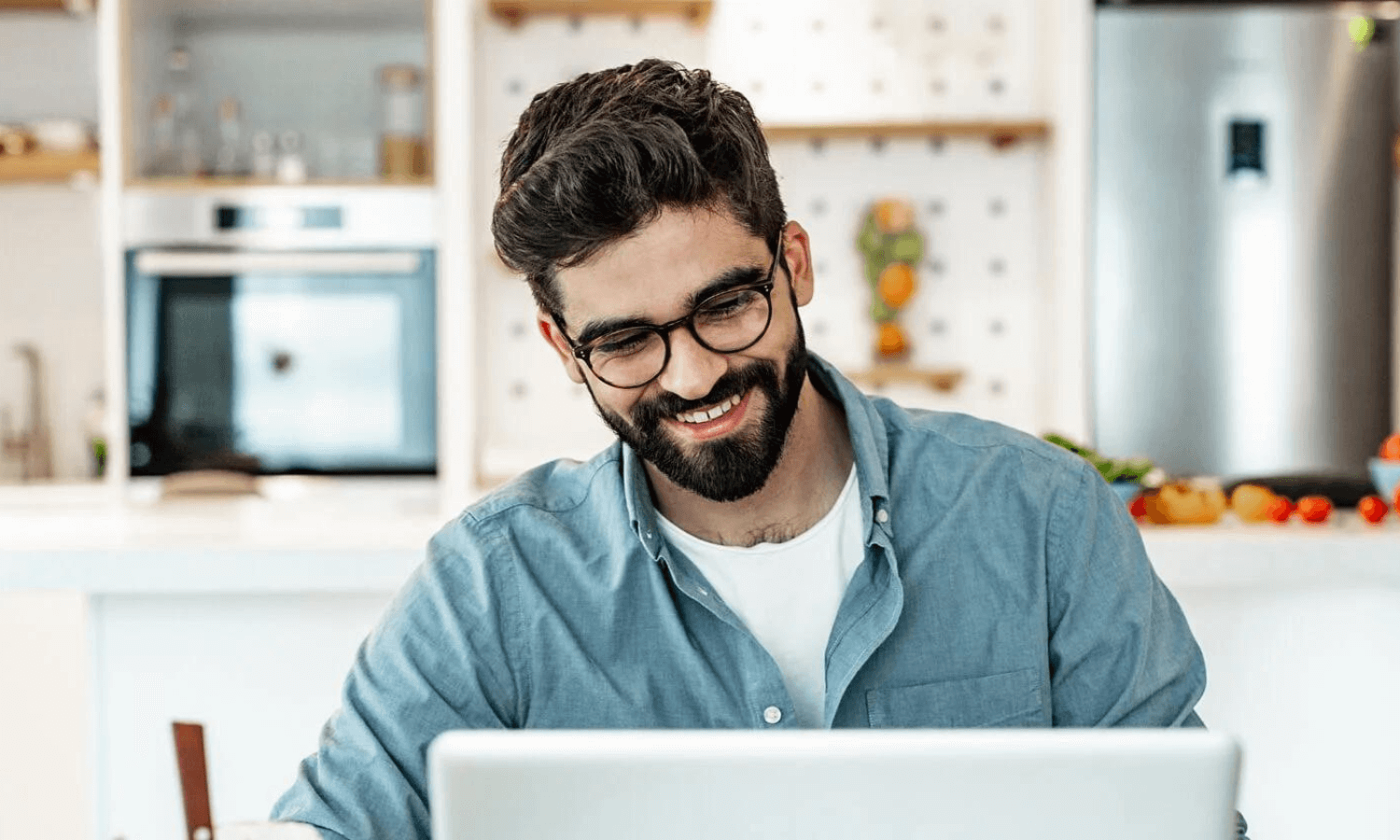 man in kitchen using laptop for remote work (1)