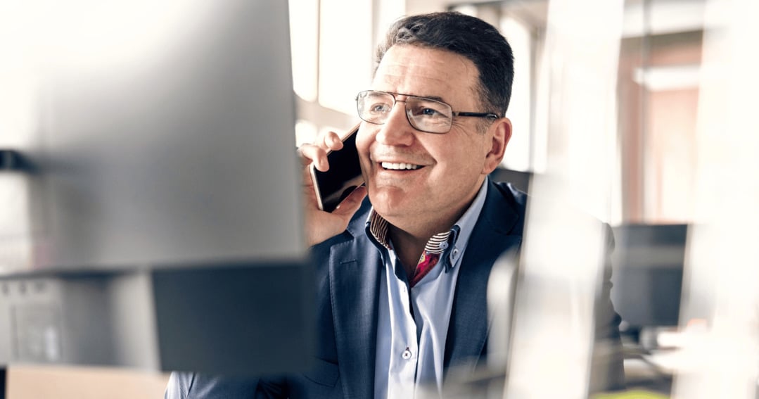 Man on the phone in office next to computer