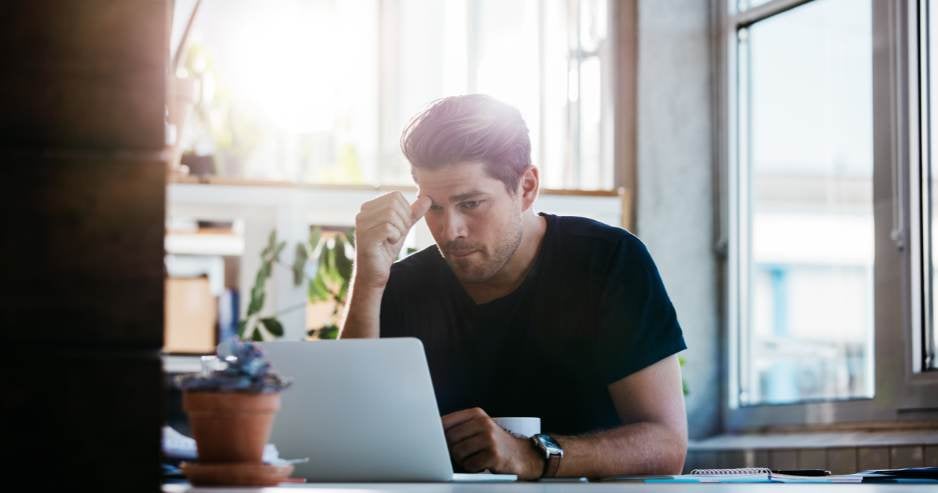 Man thinking about password safety in front of laptop