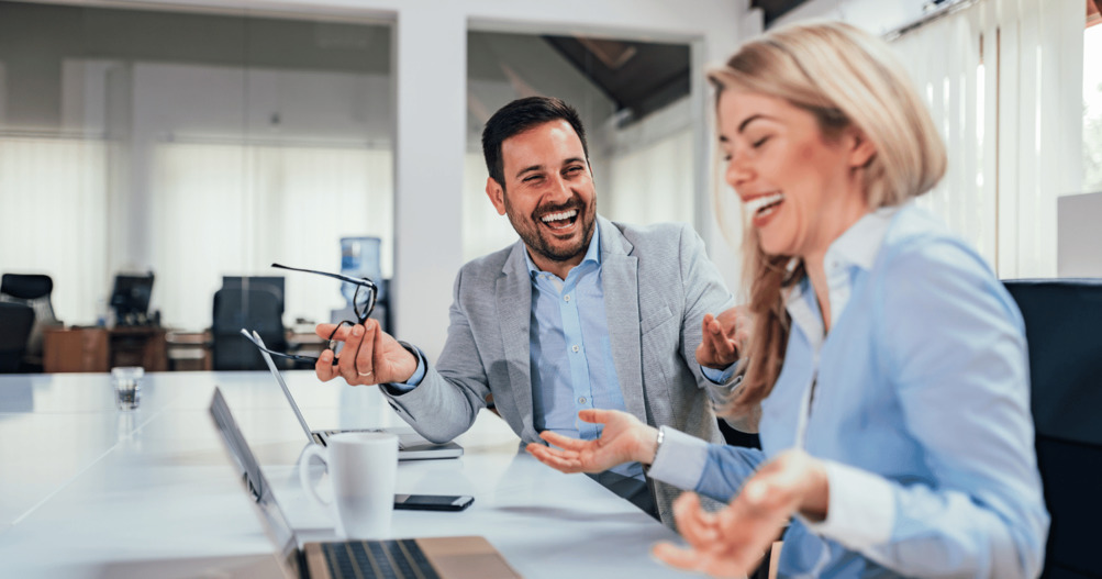 Pair of colleagues at desk drinking coffee