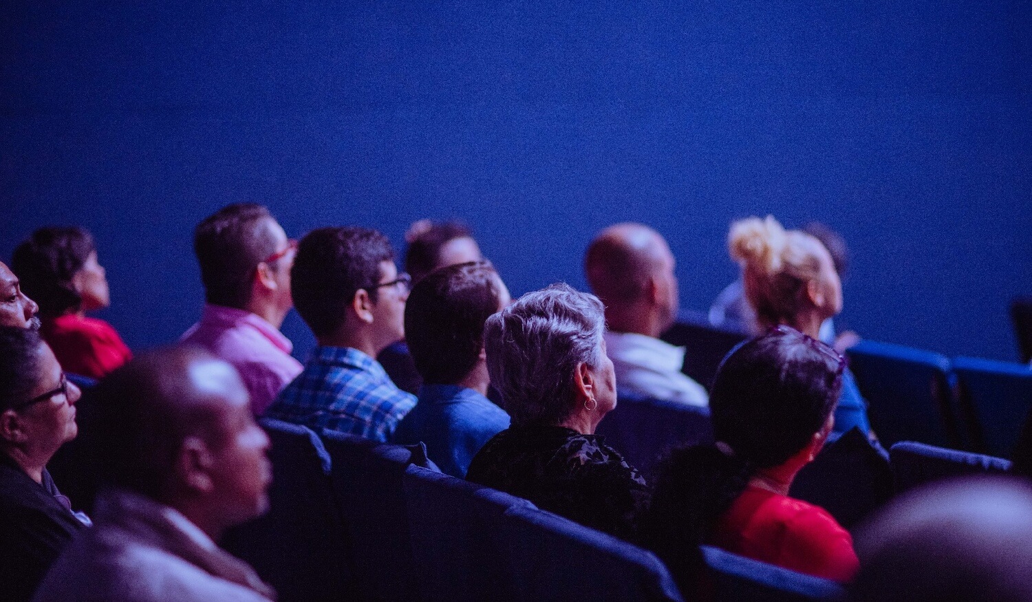 people at conference watching video in dark room