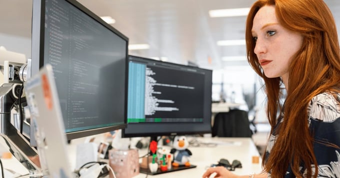 Woman IT manager using computers in office to analyse code