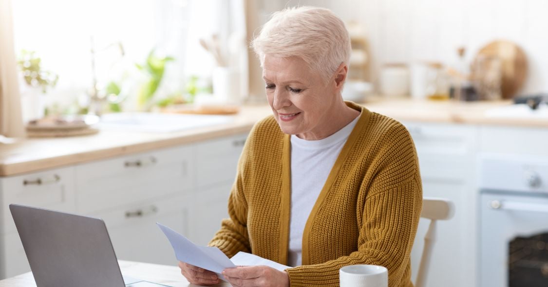 Older female opening letters in the kitchen