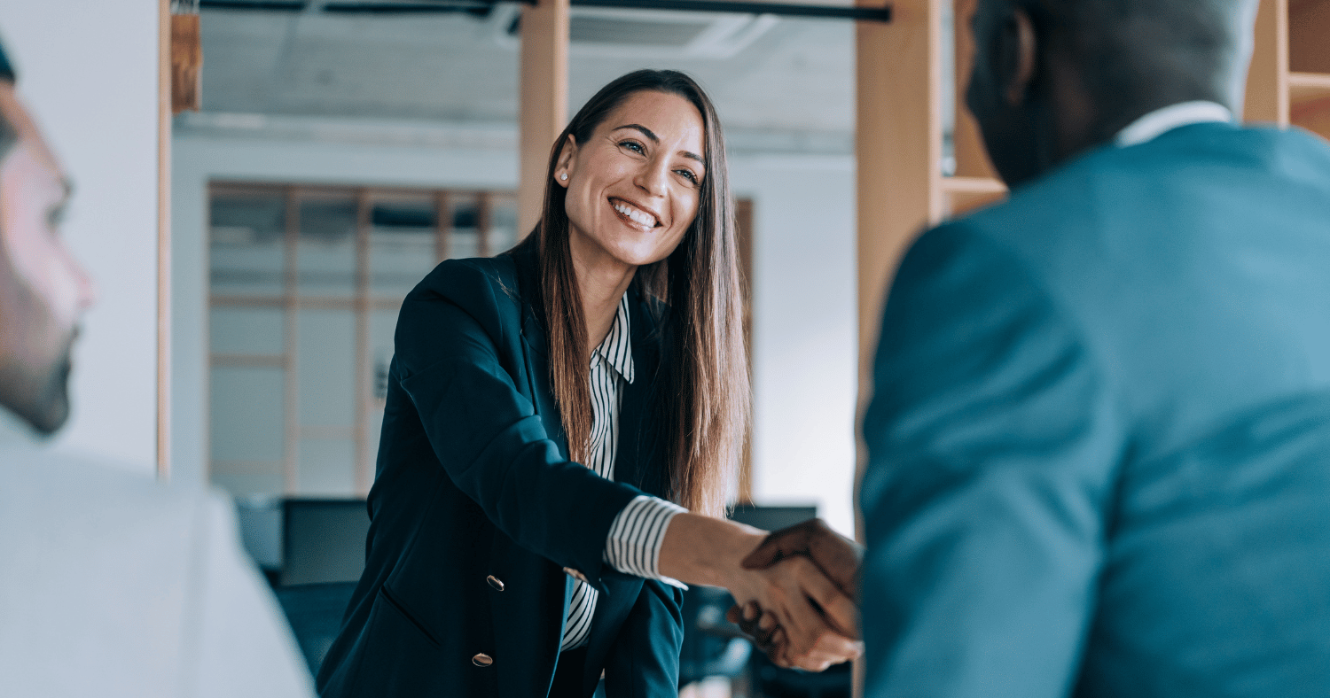 Woman shaking hands with two men in an office