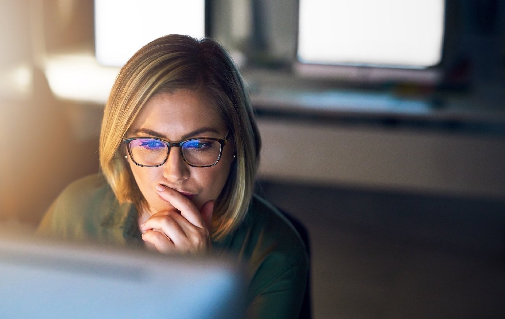 woman with glasses on looking intently at computer screen reviewing email security looking right-2